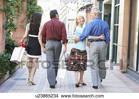 Picture - Middle-aged Couples walking holding hands hugging on Shopping Trip back view. Fotosearch