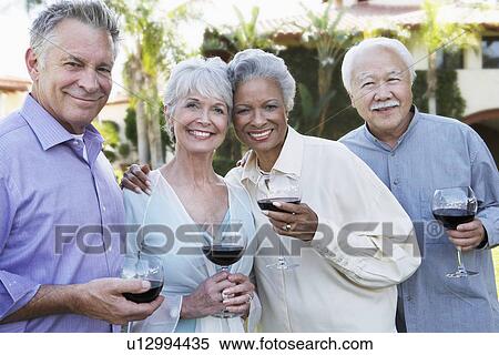 Stock Photography - Middle-aged Friends standing outside Drinking Wine from wineglasses. Fotosearch