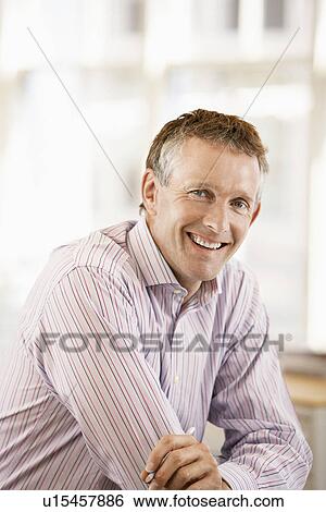 Stock Photograph - Middle-aged male office worker leaning on cubicle portrait. Fotosearch