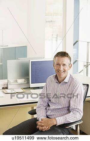 Stock Photo - Middle-aged male office worker sitting in cubicle portrait. Fotosearch