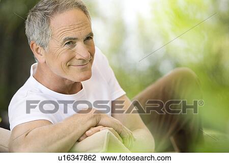Middle-aged man reclining on deck chair in garden View Large Photo Image Stock Image - Middle-aged man reclining on deck chair in garden. Fotosearch