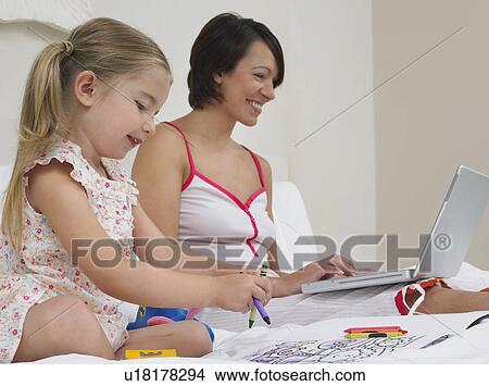 Mother and daughter drawing and using laptop on bed View Large Photo Image Picture - Mother and daughter drawing and using laptop on bed. Fotosearch