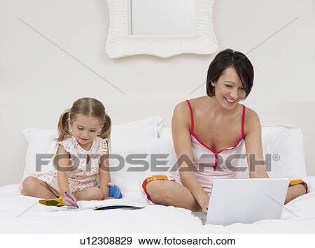 Mother and daughter drawing and using laptop on bed View Large Photo Image Stock Photo - Mother and daughter drawing and using laptop on bed. Fotosearch