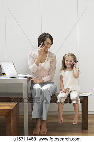 Stock Photo - Mother and daughter using cell phones. Fotosearch
