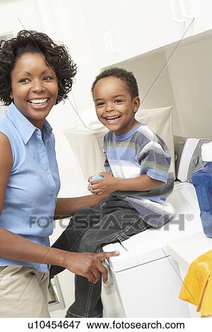 Stock Photo - Mother and son (3-6) in laundry room. Fotosearch
