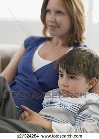 Picture - Mother and son (5-6) watching television on couch. Fotosearch