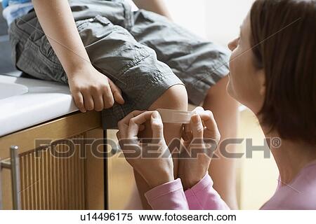 Mother Applying plaster to knee of son focus on knee View Large Photo Image Stock Photography - Mother Applying plaster to knee of son focus on knee. Fotosearch