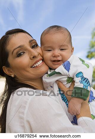 Mother embracing baby (6-12 months) outdoors (portrait) View Large Photo Image Picture - Mother embracing baby (6-12 months) outdoors (portrait). Fotosearch
