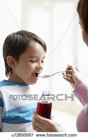 Stock Photo - Mother Giving Son Cough Syrup. Fotosearch