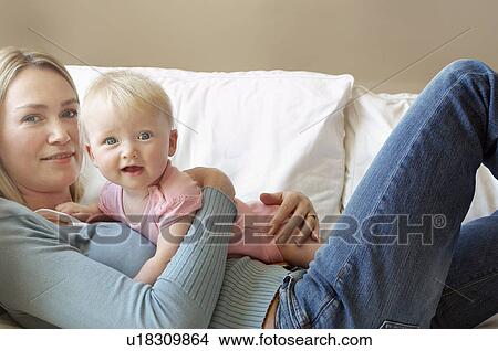 Picture - Mother with daughter on sofa. Fotosearch