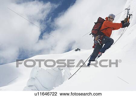 Mountain climber going up snowy slope with axes View Large Photo Image Stock Image - Mountain climber going up snowy slope with axes. Fotosearch