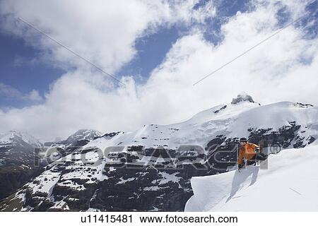 Stock Image - Mountain climber reaching peak. Fotosearch