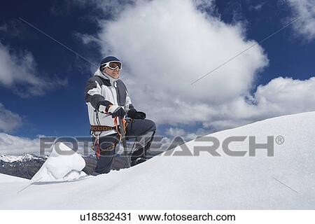 Stock Image - Mountain climber reaching snowy peak. Fotosearch