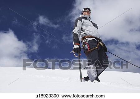 Mountain climber standing on snowy slope with safety line attached View Large Photo Image Stock Image - Mountain climber standing on snowy slope with safety line attached. Fotosearch