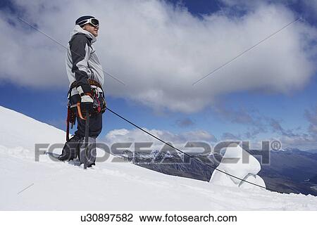 Mountain climber standing on snowy slope with safety line attached View Large Photo Image Stock Image - Mountain climber standing on snowy slope with safety line attached. Fotosearch