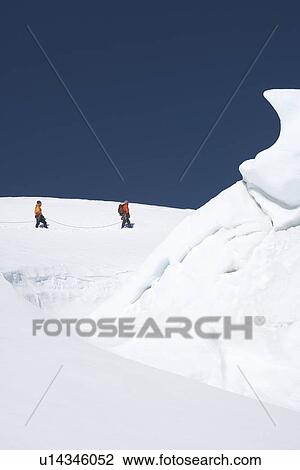 Mountain climbers walking past ice formation View Large Photo Image Stock Image - Mountain climbers walking past ice formation. Fotosearch