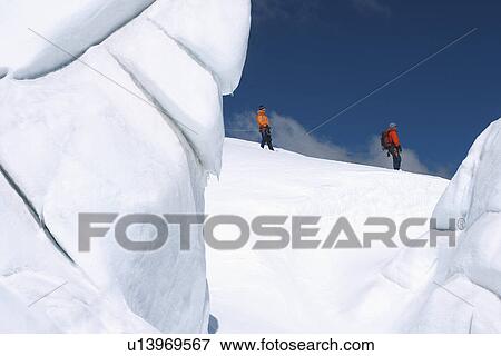 Mountain climbers walking past ice formation View Large Photo Image Stock Photo - Mountain climbers walking past ice formation. Fotosearch