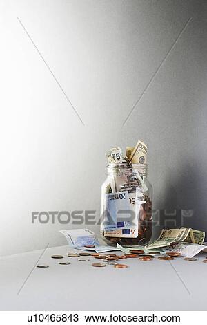 Notes and coins overflowing from jar View Large Photo Image Stock Image - Notes and coins overflowing from jar. Fotosearch