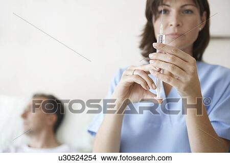 Nurse Preparing syringe For Injection focus on syringe View Large Photo Image Picture - Nurse Preparing syringe For Injection focus on syringe. Fotosearch