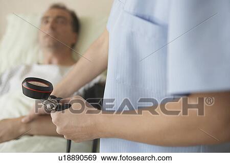 Nurse Taking blood pressure and pulse of patient in hospital bed mid section of nurse focus on gauge View Large Photo Image Stock Photo - Nurse Taking blood pressure and pulse of patient in hospital bed mid section of nurse focus on gauge. Fotosearch