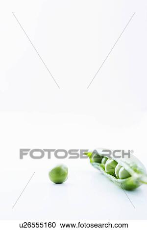 Stock Image - Open pea pod containing peas and single pea close-up. Fotosearch