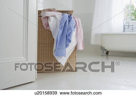 Stock Photo - Overflowing laundry basket in bathroom. Fotosearch