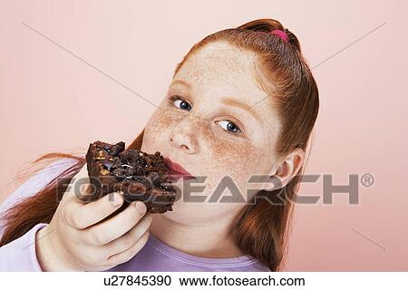 Stock Image - Overweight girl (13-15) Eating brownie portrait close-up. Fotosearch