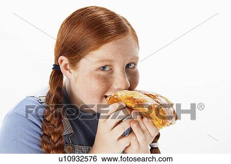 Stock Photograph - Overweight girl (13-15) eating doughnut portrait. Fotosearch