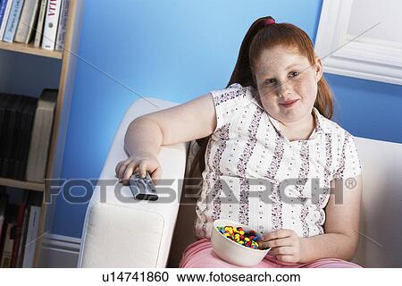 Overweight girl (13-15) Eating Junk Food holding remote control View Large Photo Image Stock Image - Overweight girl (13-15) Eating Junk Food holding remote control. Fotosearch
