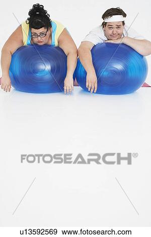Overweight man and woman lying on Exercise Balls portrait front view View Large Photo Image Stock Photo - Overweight man and woman lying on Exercise Balls portrait front view. Fotosearch