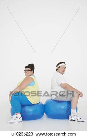 Overweight man and woman sitting back to back on exercise balls portrait View Large Photo Image Stock Image - Overweight man and woman sitting back to back on exercise balls portrait. Fotosearch