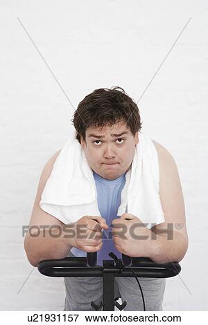 Stock Photo - Overweight man on Exercise Bike portrait. Fotosearch