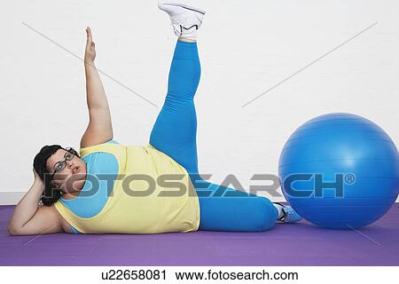 Overweight Woman lying by exercise ball stretching arm and leg upwards View Large Photo Image Stock Image - Overweight Woman lying by exercise ball stretching arm and leg upwards. Fotosearch