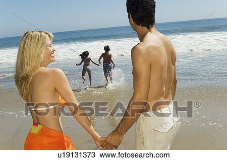 Parents watching children running into sea holding hands View Large Photo Image Stock Image - Parents watching children running into sea holding hands. Fotosearch