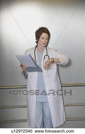 Stock Image - Physician Checking Wristwatch in elevator. Fotosearch