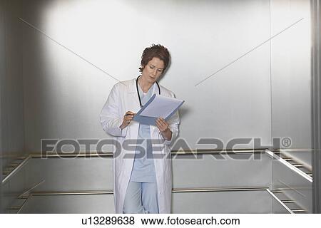 Physician Reviewing Notes in elevator View Large Photo Image Stock Photo - Physician Reviewing Notes in elevator. Fotosearch