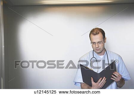 Physician Reviewing Notes in elevator View Large Photo Image Stock Photography - Physician Reviewing Notes in elevator. Fotosearch