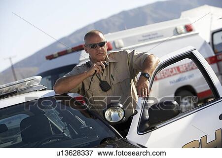 Police officer using two-way radio by police car View Large Photo Image Stock Photo - Police officer using two-way radio by police car. Fotosearch