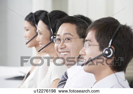 Stock Photo - Row of customer service representatives wearing telephone headsets in office head and shoulders. Fotosearch