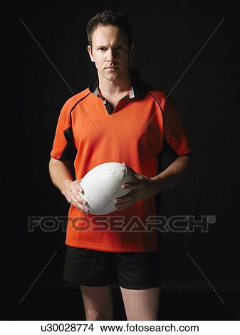 Picture - Rugby player standing holding ball portrait. Fotosearch