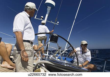 Sailors at helm of sailboat View Large Photo Image Stock Image - Sailors at helm of sailboat. Fotosearch