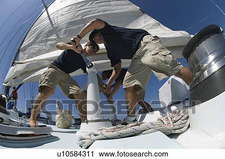 Sailors operating windlass on yacht low angle view View Large Photo Image Stock Image - Sailors operating windlass on yacht low angle view. Fotosearch