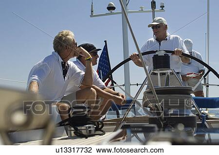 Stock Image - Sailors talking at Helm on Yacht. Fotosearch