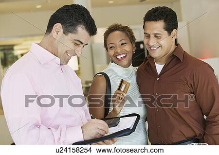 Salesperson Calculating purchase amount of couple in furniture store View Large Photo Image Picture - Salesperson Calculating purchase amount of couple in furniture store. Fotosearch