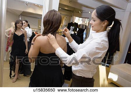 Saleswoman assisting customer with dress side view View Large Photo Image Stock Image - Saleswoman assisting customer with dress side view. Fotosearch