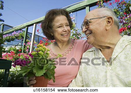 Senior Couple sitting among flowers at plant nursery close up View Large Photo Image Picture - Senior Couple sitting among flowers at plant nursery close up. Fotosearch