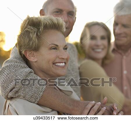 Stock Photo - Senior couples relaxing together on beach. Fotosearch