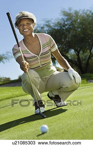 Stock Image - Senior woman on golf course (portrait). Fotosearch