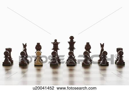 Stock Image - Single white pawn in initial line up of black chess pieces. Fotosearch