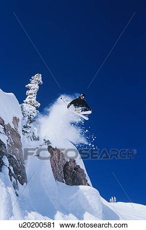 Stock Image - Skier jumping from mountain ledge. Fotosearch